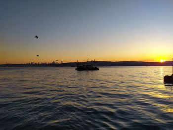 Silhouette boats in sea against sky during sunset