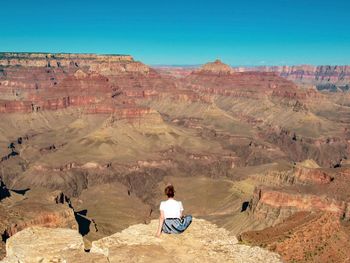 Reat view of woman sitting on rock admiring the  the view at grand canyon