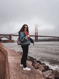 Full length of woman standing on bridge over sea against sky