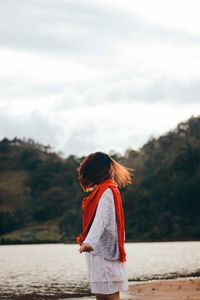 Rear view of woman standing on beach against sky