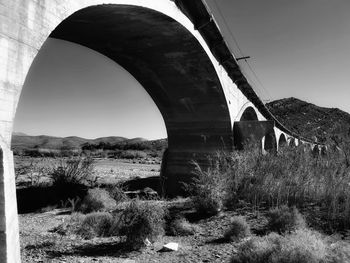 Arch bridge on field against clear sky