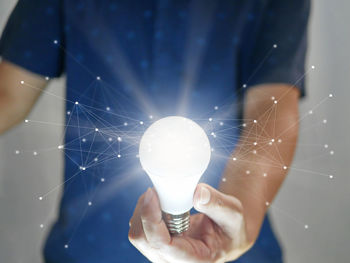 Digital composite image of man holding light bulb