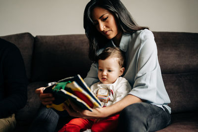 Happy mother and daughter sitting on sofa