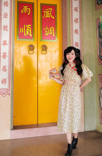 Young woman standing against wall