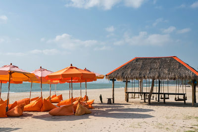 Orange seats and parasol on beach with chairs by sea with blue sky at cha-am beach, petchaburi