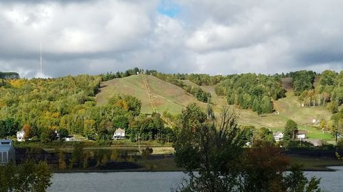 Scenic view of river by trees against sky