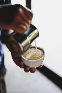 Midsection of person pouring coffee in cup