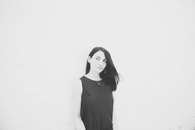 Portrait of a young woman standing against wall