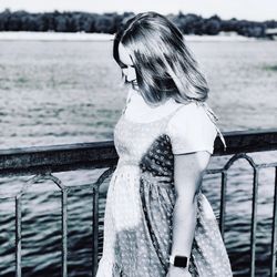 Woman standing by railing against sea