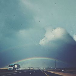 Cars on road against cloudy sky