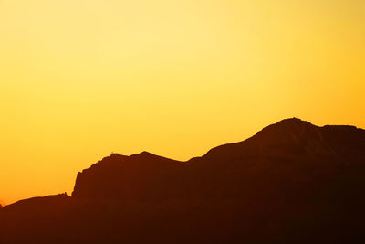 Scenic view of silhouette mountains against orange sky