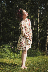 Young woman standing against tree in park