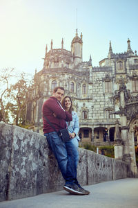 Portrait of couple standing against building