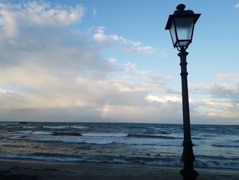 Street light by sea against sky