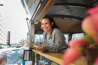 Smiling mid adult female owner at food truck in city