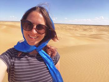Portrait of smiling young woman wearing sunglasses on sand