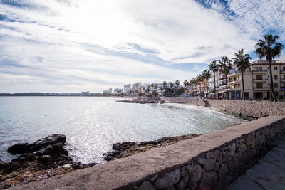 Scenic view of sea by city buildings against sky