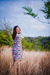 Happy woman standing on field against sky