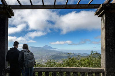 Rear view of men standing on mountain against sky