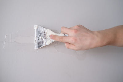 Cropped hand of person holding paper currency against gray background