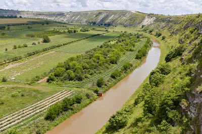 Small house on the river bank surrounded by green vegetation.