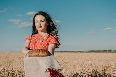 Portrait of woman standing on field against sky