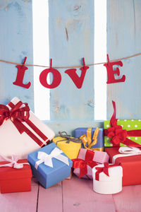 Gifts on table with love text hanging on wall