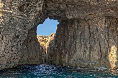 Rock formation in sea against sky