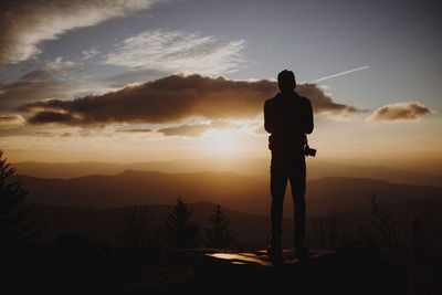 Silhouette man standing against sky at sunset