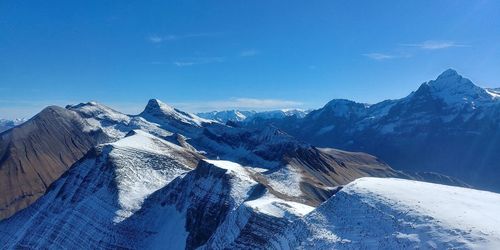 Scenic view of snowcapped mountains against blue sky