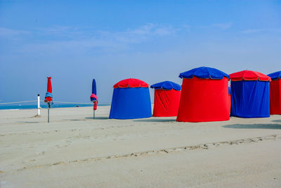 Multi colored umbrellas on beach against blue sky