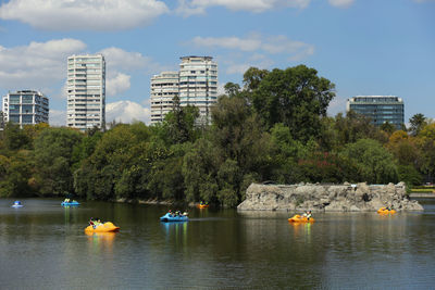 Boats in lake against buildings in city