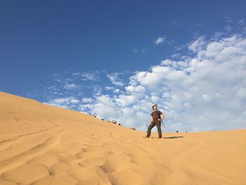 Man on sand dune in desert against sky