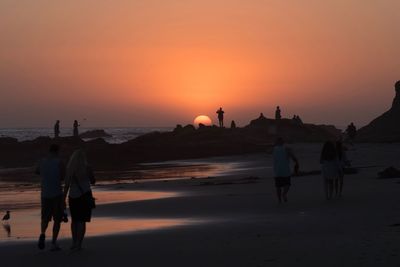 Rear view of people on beach during sunset