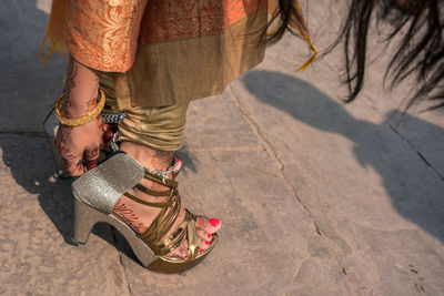 Low section of woman wearing high heels on footpath