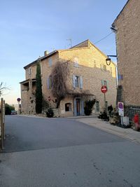 Street amidst buildings against clear blue sky