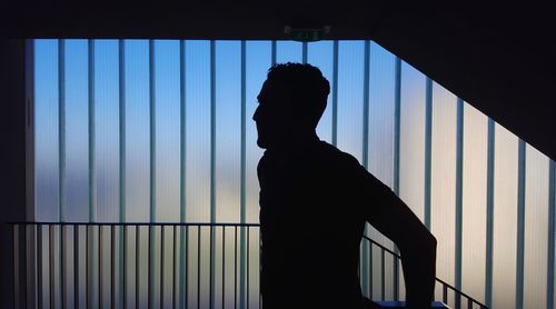 Silhouette man standing by railing in building