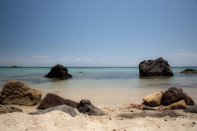 Scenic view of rocks on beach against sky