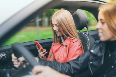 Girls sitting in the car. teen in front of the steering wheel with friend . women enjoying free time