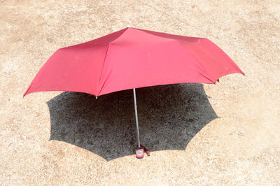 High angle view of pink umbrella on sand