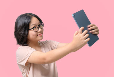 Young woman using mobile phone against blue background