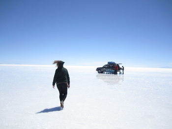 Rear view of man walking in sea against clear sky