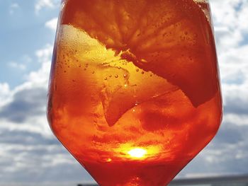 Close-up of orange drink against sky