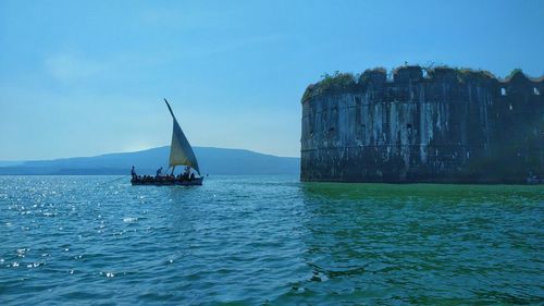 Sailboat sailing in sea against blue sky