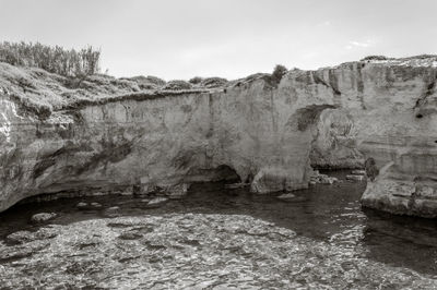 Rock formations by river against sky