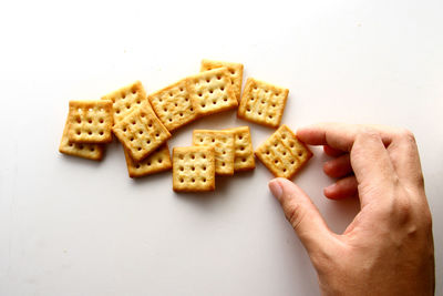 High angle view of hand holding crackers  against white background
