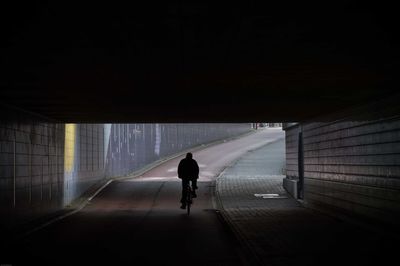 Silhouette man riding bicycle in tunnel