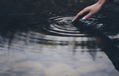 Cropped hand touching water in lake