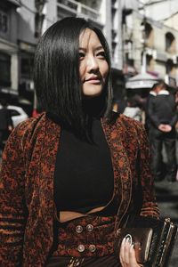 Young woman looking away while standing on street