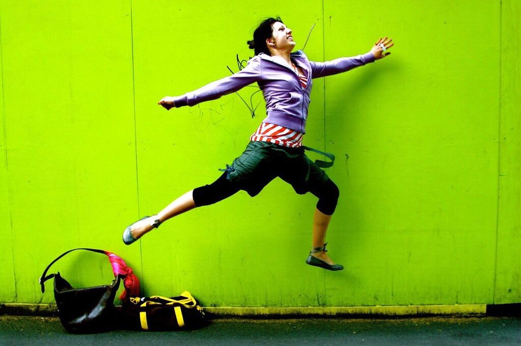FULL LENGTH OF YOUNG WOMAN JUMPING IN MID-AIR